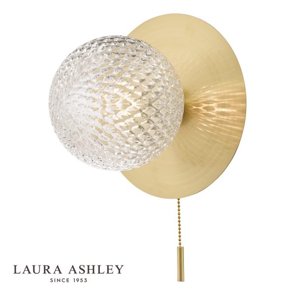 Prague switched bathroom wall light in satin brass finish on white background, lit.