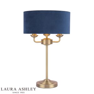 Laura Ashley Sorrento 3 light table lamp in matt antique brass with blue shade, on white background, lit.