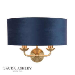 Laura Ashley Sorrento 2 light wall light in matt antique brass with blue shade, on white background, lit.