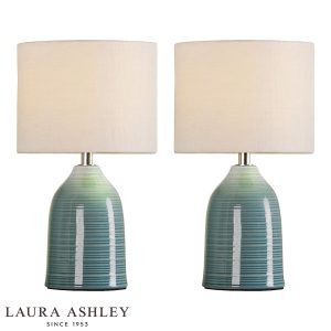 Penny blue ceramic table lamp on white background, lit.