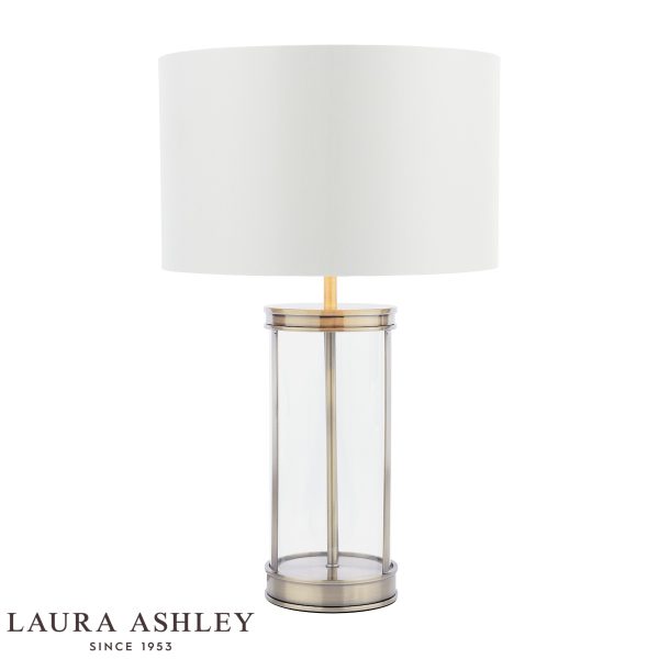 Harrington small glass table lamp in antique brass finish with ivory linen shade by Laura Ashley, on white background, lit.