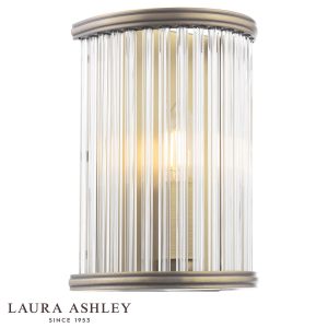 Sutton single wall light in matt antique brass finish with clear glass rods by Laura Ashley, on white background, lit.
