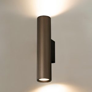 Franklite Scout modern up and down wall light in bronze, on cream wall, lit.