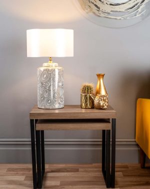 Ayesha ivory and gold ceramic jar table lamp with white linen shade shown on lounge table