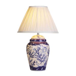 Devana blue and white ceramic table lamp with ivory shade on white background with shade lit
