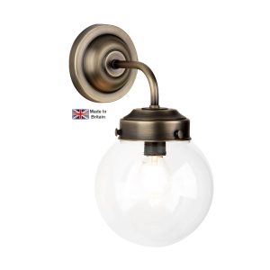 Fairfax single wall light in solid antique brass with clear glass shade on white background lit