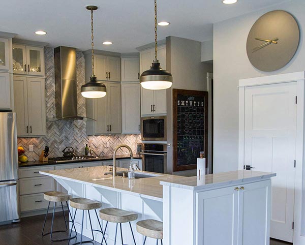 Kitchen diner with two pendants over a breakfast bar and downlights.