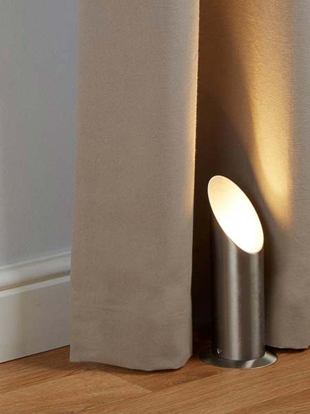 Satin silver floor uplighter next to curtains