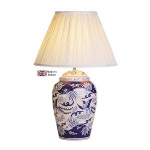 Fawkes blue and white ceramic table lamp with ivory shade on white background lit