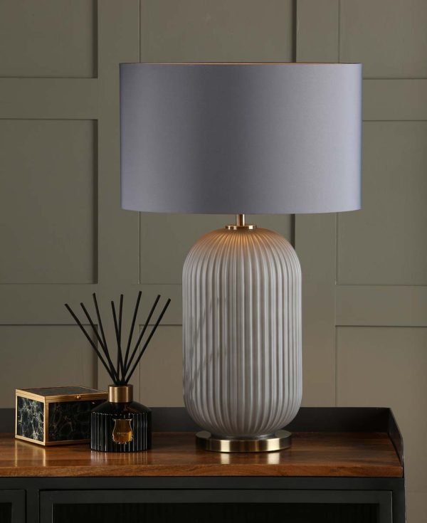 Helicon grey ribbed glass table lamp with grey faux silk shade, shown lit on sideboard in room setting