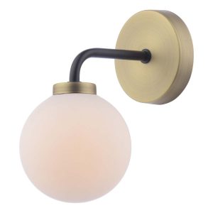 Lainey single wall light in antique brass with opal glass globe shade, on white background lit