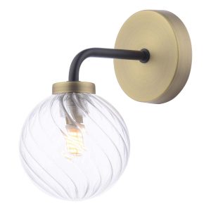 Lainey single wall light in antique brass with twisted clear glass globe shade on white background lit