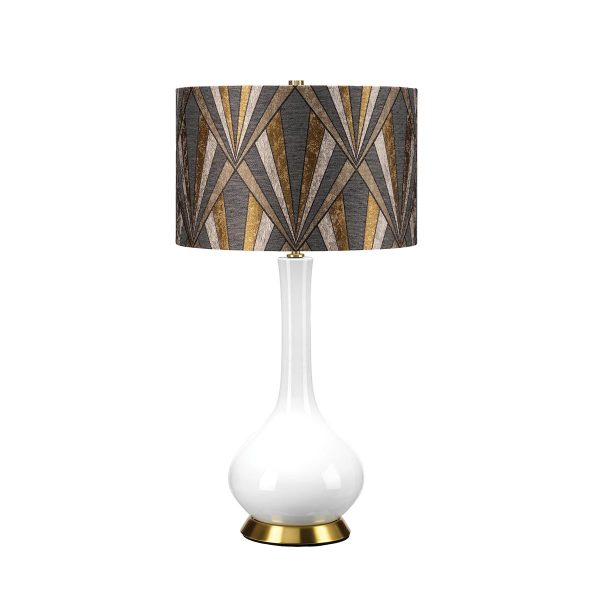Milo white ceramic table lamp with aged brass metalwork and geometric patterned shade, on white background, lit.