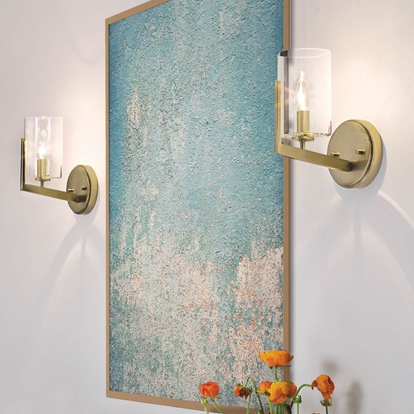 Nye wall light in natural brass, shown lit on either side of wall art in room setting.