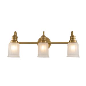 Quoizel Swell 3 light bathroom wall light in brushed brass finish with frosted glass shades on white background lit