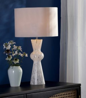 Rheneas white confetti glass table lamp with ivory shade, shown lit on living room sideboard