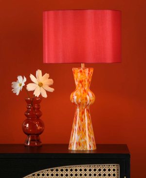 Rheneas red confetti glass table lamp with red shade, shown lit on lounge sideboard