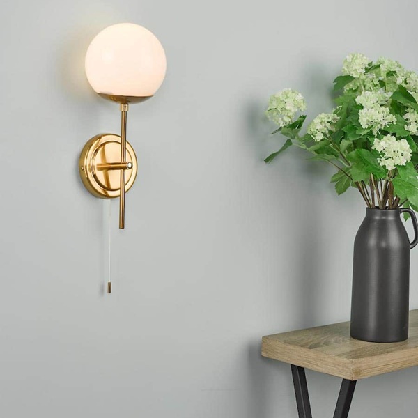 Bombazine wall light in solid natural brass, shown next to a hall table.